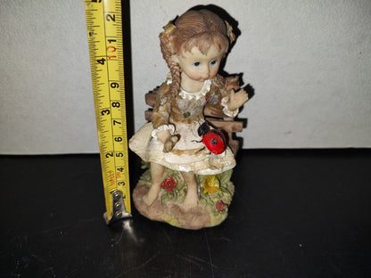 A6- Figura De Resina: Niña De Trenzas Sentada En Banca De Madera Con Mariquita En Las Piernas - 80'S