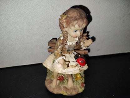 A6- Figura De Resina: Niña De Trenzas Sentada En Banca De Madera Con Mariquita En Las Piernas - 80'S