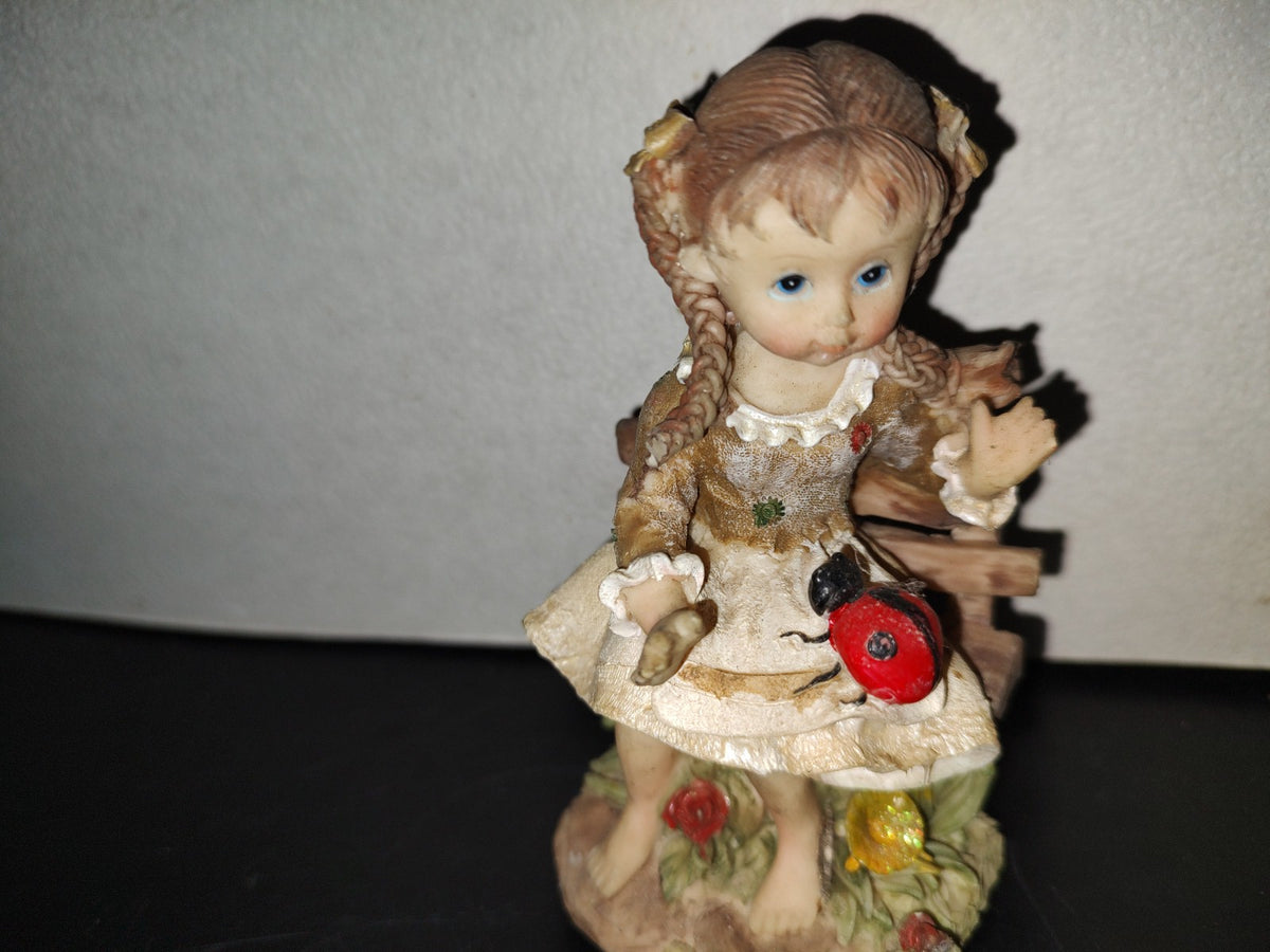 A6- Figura De Resina: Niña De Trenzas Sentada En Banca De Madera Con Mariquita En Las Piernas - 80'S